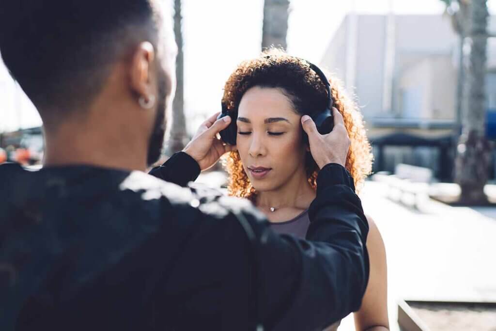 man sets woman headphones on ready to train