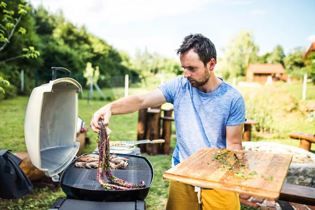 man prepares food on grill