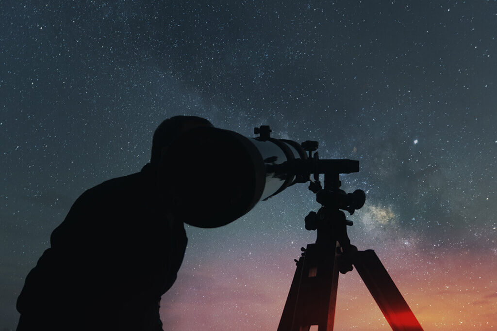 Man looking at starry sky with telescope