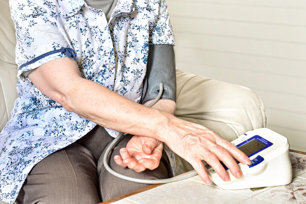 Torso of an elderly lady measuring her blood pressure.
