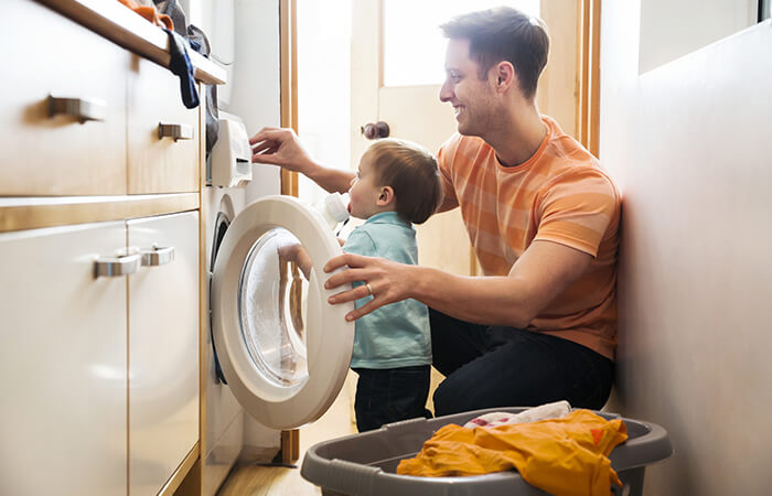 father and child operating washing machine