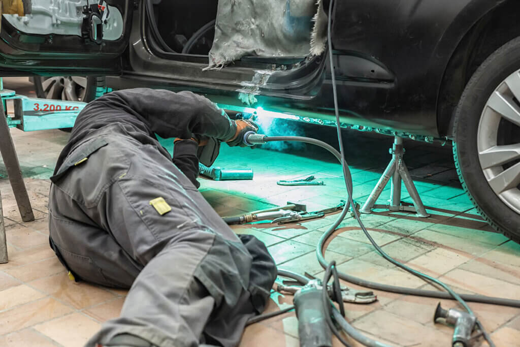 Person in workshop welding on car