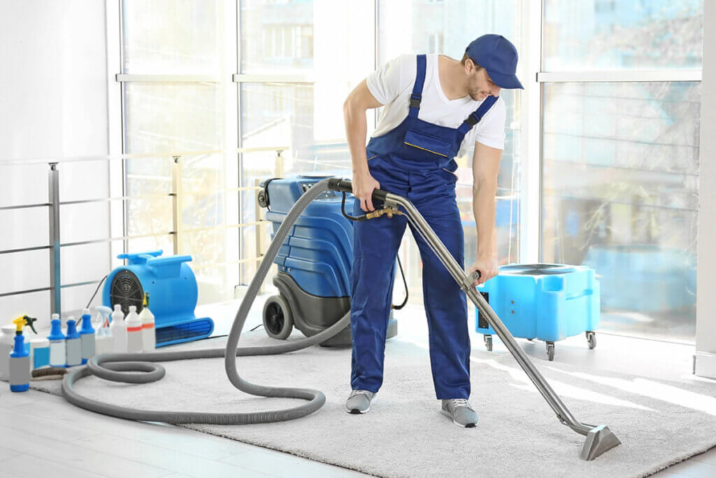 man cleans carpet in building with wet vacuum cleaner