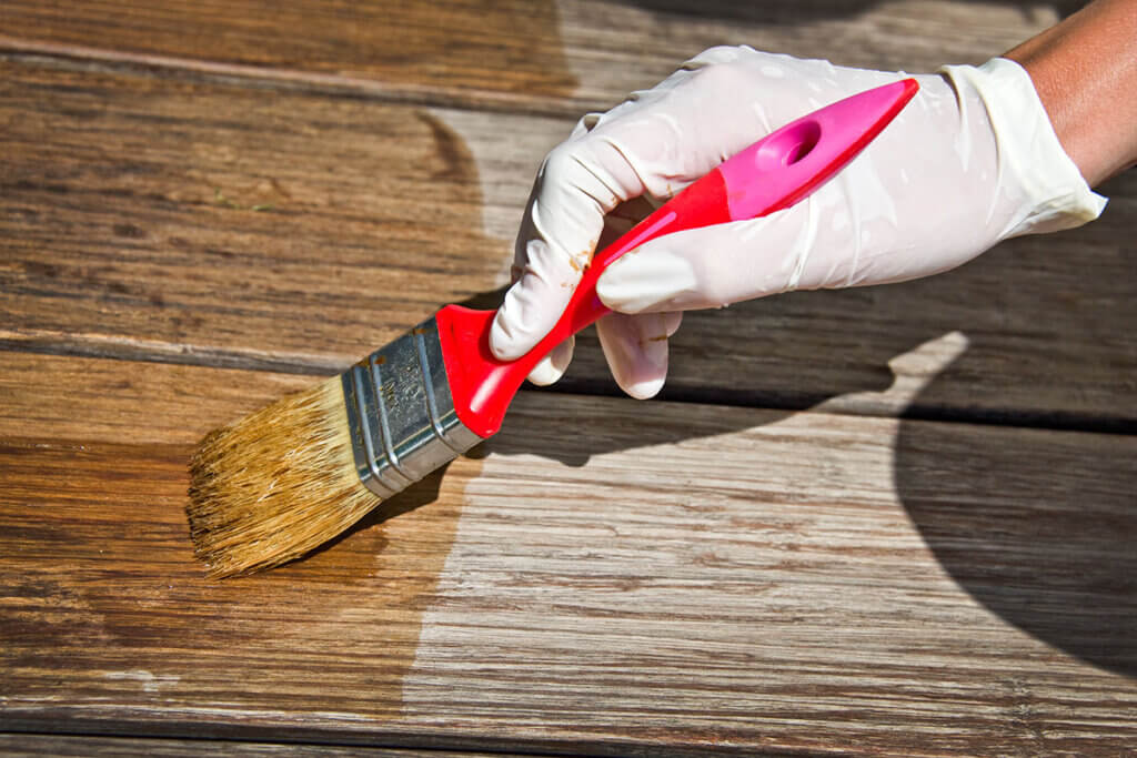 Person wears gloves when painting wood stain